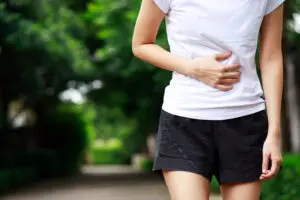 Woman walking outside holding her stomach for pain